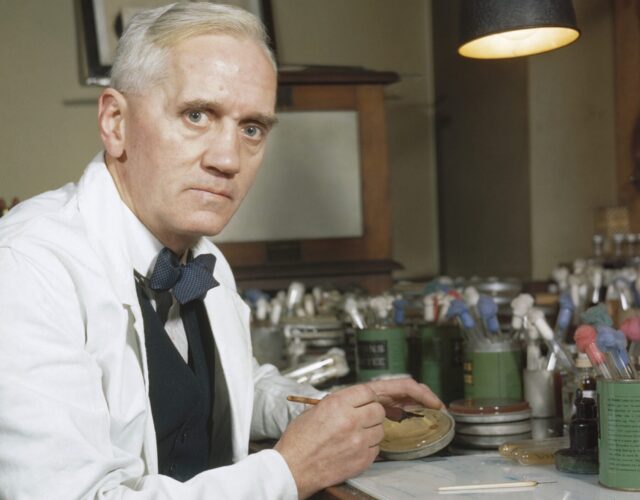 Alexander Fleming working in a lab holding a petri dish