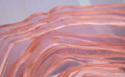 Detail of a pink translucent glass sculpture with wavy lines